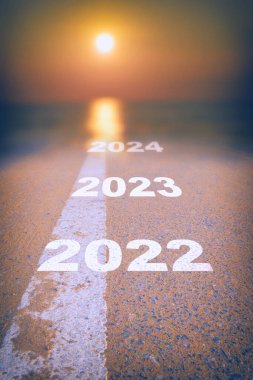 2022 'den 2024' e kadar asfalt yol yüzeyinde soyut bulanık güneş ışığı ve güneşe giden beyaz işaret çizgisi var. Sürdürülebilir iş stratejisi kavramına başla