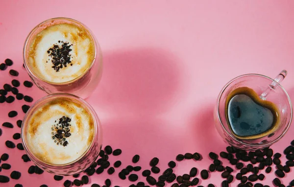 Pembe arka planda sütlü taze espresso kahve fincanları. Yukarıdan görüntüle