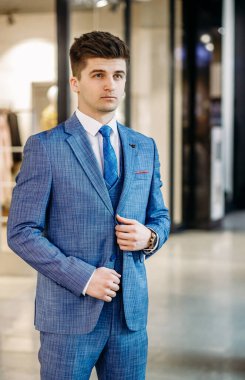 Şık mavi takım elbiseli, kravatlı ve beyaz gömlekli yakışıklı, zarif bir adam. Tam uzunluk.