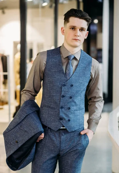 Young attractive businessman or director stylishly dressed stands with his hands in his pocket and looks at the camera