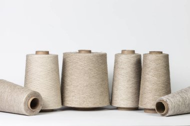 Beyaz arkaplanda izole edilmiş büyük keten iplik makaraları.