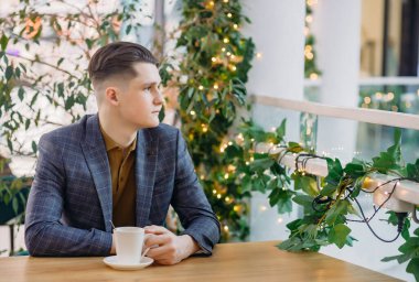 Genç işadamı öğle yemeği molasında. Yakışıklı akıllı adam öğle yemeği sırasında modern kafede kahve içiyor..