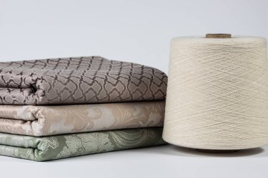 Beyaz zemin üzerinde iplik ve eşit katlanmış kumaş ile büyük bobbin.