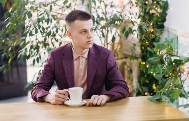 Mola sırasında ofiste kahve içen genç bir müdür.