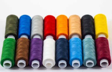 Beyaz arkaplanda iplik izole edilmiş çok renkli bobinler var..