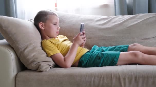 Młody chłopiec gra w smartfon. — Wideo stockowe