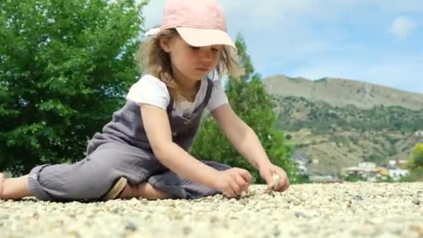 Little cute girl playing with pebbles. — Stock Video