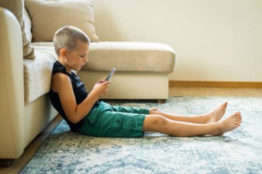 Akıllı telefonla oynayan genç bir çocuk..