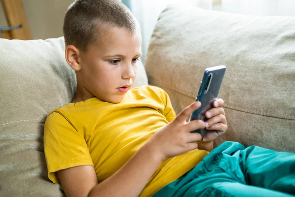 Ung pojke spelar i smartphone. — Stockfoto