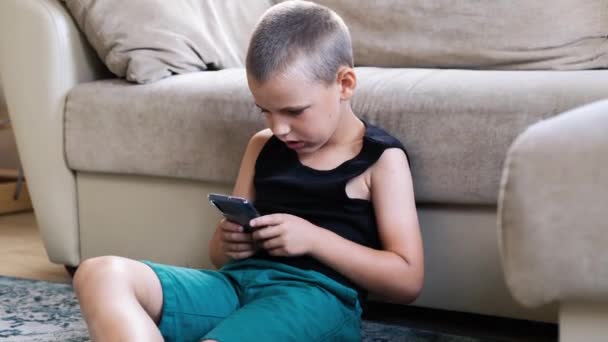 Młody chłopiec gra w smartfon. — Wideo stockowe