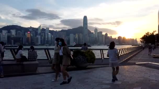 Hong Kong, China, 22 de outubro de 2020: Pôr-do-sol em frente à água Tsim Sha Tsui; a população local desfruta do pôr-do-sol à beira-mar — Vídeo de Stock