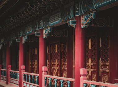 Pekin, Çin 'deki mimari detaylara odaklanarak, bu resim canlı kırmızı sütunları ve geleneksel bir yapının zarif süslenmiş kapılarını yakalıyor..
