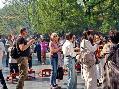 Sep 24 2025 - Pekin, Çin: Pekin 'deki Yonghegong Lama Tapınağı' nda canlı bir sahne, geleneksel bir dini faaliyete katılan bir grup insanı, elinde tütsü ve tütsü tutan bir kadın üzerine yoğunlaşarak yakıyor..