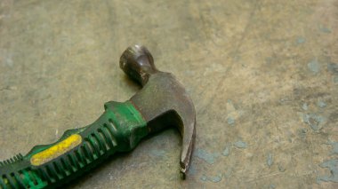 Yerde yeşil lastik saplı küçük bir çekiç. Bir nesnenin küçük bir bölgesine etki etmesi için uzun bir sapa sabitlenmiş ağırlıklı bir 