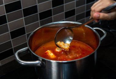 Metal bir kepçeyle Oden 'ı sıcak tencerenin içinde yapmak için malzemeleri karıştıran el görüntüsünü kapat. Meşhur bir Japon sokak yemeği..