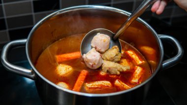 Metal bir kepçeyle Oden 'ı sıcak tencerenin içinde yapmak için malzemeleri karıştıran el görüntüsünü kapat. Meşhur bir Japon sokak yemeği..