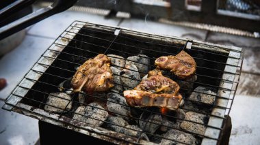 Piknik partisinde sıcak dumanlı mangalda pişirilmiş sosla marine edilmiş çiğ kuzu etinin yakın görüntüsü. Önplanda seçmeli odak.