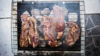 Piknik partisinde sıcak dumanlı mangalda pişirilmiş sosla marine edilmiş çiğ kuzu eti manzarası. Önplanda seçmeli odak.