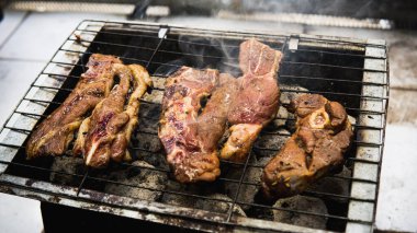 Piknik partisinde sıcak dumanlı mangalda pişirilmiş sosla marine edilmiş çiğ kuzu etinin yakın görüntüsü. Önplanda seçmeli odak.