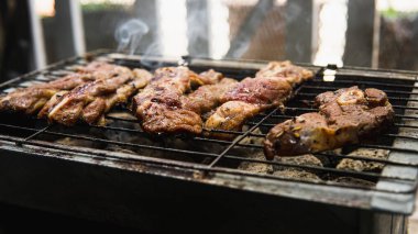 Piknik partisinde sıcak dumanlı mangalda pişirilmiş sosla marine edilmiş çiğ kuzu etinin yakın görüntüsü. Önplanda seçmeli odak.