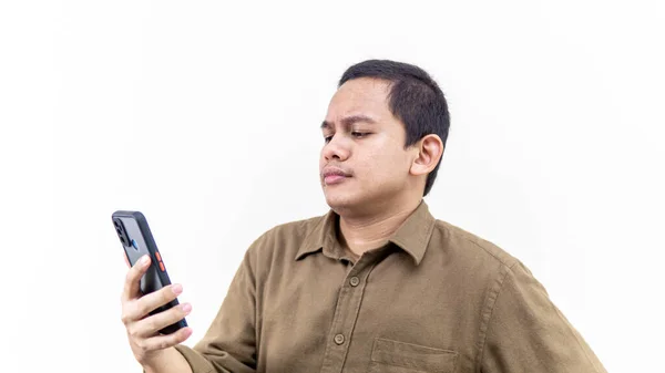年轻的亚裔马来人脸上困惑 怀疑和怀疑的表情 在孤立的白色背景下看着智能手机 — 图库照片