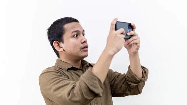 严肃而专注的表情 年轻的亚裔马来人看着智能手机孤立的白色背景 在手机上玩网络游戏 — 图库照片