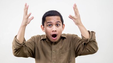 Akıllara zarar. İki eli havada ve ağzı açık, izole beyaz arka planı olan Asyalı genç Malezyalı adamın şok olmuş yüz ifadesi. Reklam modeli konsepti.