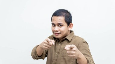 Genç Asyalı Malezyalı adamın kamerayı ve öndekileri işaret eden kendinden emin ve mutlu yüz ifadesi. Konseptini seçiyorum..