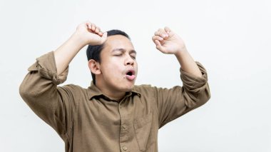 Genç Asyalı Malezyalı adamın mutlu ve heyecanlı yüz ifadesi. Dans ediyor ve müziğin ritmini tenha beyaz arka planda hissediyor. Neşeli, güler yüzlü, rahat ve kendinden emin bir şekilde müzik dinliyor..