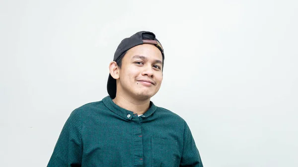 一幅年轻的亚裔马来人的画像 戴着黑色的帽子 穿着休闲的绿色衬衫 对着摄像机微笑 白色的背景与镜头隔离 — 图库照片