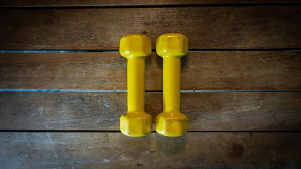 顶部视图一对1公斤的黄色迷你哑铃木制背景 锻炼工具和健身设备 — 图库照片