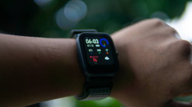 Bileğinde renkli saat suratı olan akıllı bir adam görüntüsü yakın çekim. O, saat şeklinde takılabilir bir bilgisayardır. Verileri akıllı telefona senkronize edebiliyor. Nesneye seçici odaklanma.