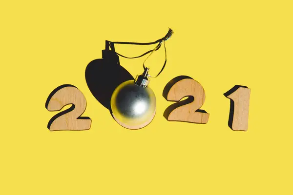 Nummer 2021 från trä bokstäver och jul boll på en gul bakgrund. — Stockfoto