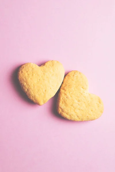 Dos galletas en forma de corazón una al lado de la otra sobre un fondo rosa. El concepto de San Valentín. — Foto de Stock