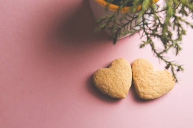 Pembe arka planda kalp şeklinde iki kurabiye yan yana. Sevgililer Günü konsepti.