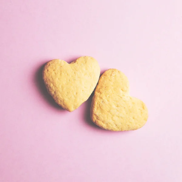 Dos galletas en forma de corazón una al lado de la otra sobre un fondo rosa. El concepto de San Valentín. — Foto de Stock