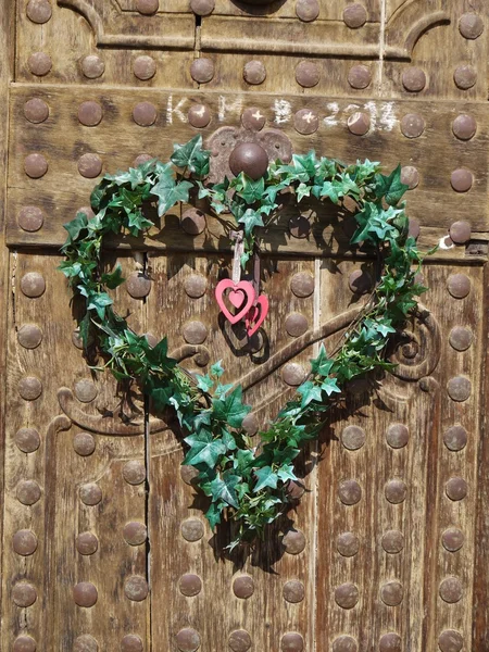 Portas de madeira velhas com coração feito de folhas verdes — Fotografia de Stock