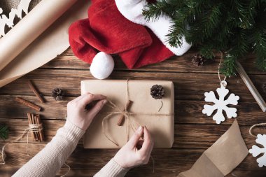Noel hediyeleri ve ahşap bir masanın üzerinde bir paket Kraft kağıdı. Yeni yıl için kırsal tarzda hediyeler yapma süreci.