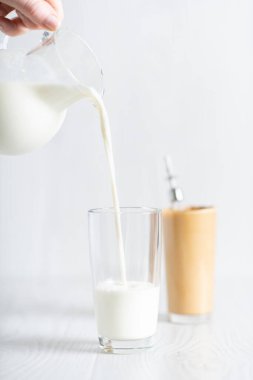 Modaya uygun bir Kore içkisi yapma süreci dalgonacoffee. Hafif arka planda sütü olan bir bardak ve sürahi..