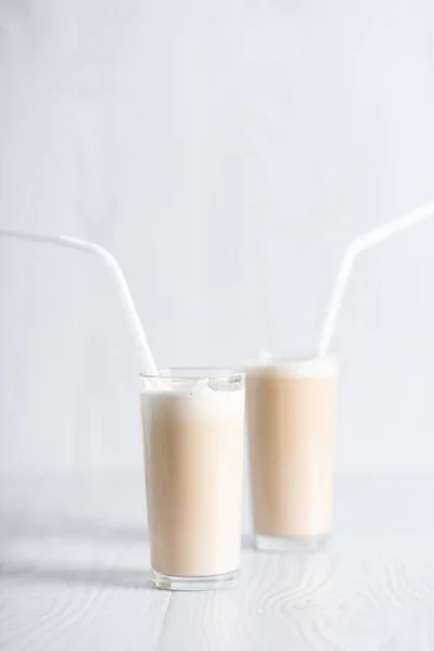 Petit déjeuner branché. Du café algon. milkshake avec café instantané et sucre, fouetté à une mousse épaisse dans des verres avec une paille sur un fond clair. — Photo