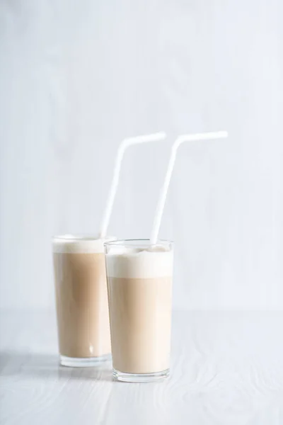 Milkshake with instant coffee and sugar, whipped to a thick foam in glasses with a straw on a light background. Trendy breakfast. Dalgon coffee — Stock Photo, Image