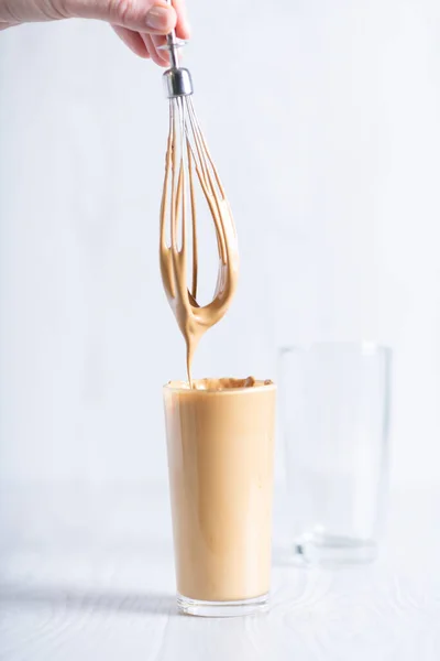 Koreanischer flauschig cremiger Schlagkaffee. Kalter Dalgonacaffee in einem Glas auf hellem Hintergrund. Eiskaffee. — Stockfoto