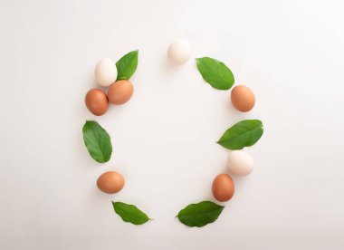 Beyaz ve kahverengi yumurta ve yeşil yapraklardan oluşan yuvarlak bir çelenk şeklinde paskalya süsü. mesaj için yer. kopyalama alanı. düz yat