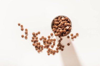 Beyaz arka planda tek kullanımlık beyaz bir fincanda çikolata parçacıkları. Üst görünüm yakın plan. Düz yatıyordu. Yumuşak çikolata şekerlemesi konsepti. Çikolata toptan satışı.