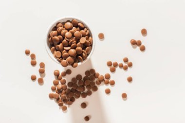 Beyaz arka planda, tek kullanımlık beyaz bir fincanda, baloncuklu çikolata. Ev yapımı tatlılar. Üst görünüm yakın plan. Düz yatıyordu. Ev yapımı pastane konsepti.