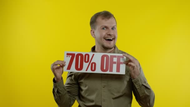 Attraktiver Mann zeigt bis zu 70 Prozent Rabatt-Schilder, freut sich über gute Rabatte, niedrige Preise — Stockvideo