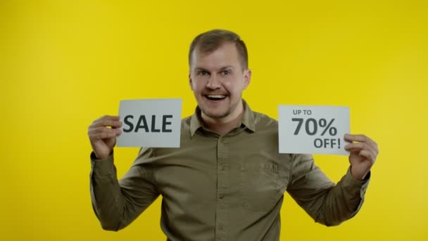 Veselý muž ukazující prodejní slovo a ukazující až 70% slevu na nápisu. Koncept Černého pátku — Stock video