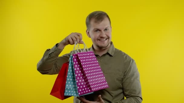 Man raising shopping bags, looking satisfied with purchase, enjoying discounts on Black Friday — Stock Video