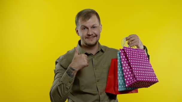 Hombre alegre mostrando la inscripción Viernes Negro de las bolsas de la compra, sonriendo satisfecho con los precios bajos — Vídeos de Stock