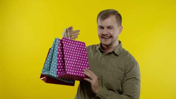 Vreugdevolle man met zwarte vrijdag inscriptie uit boodschappentassen, glimlachend tevreden met lage prijzen — Stockvideo